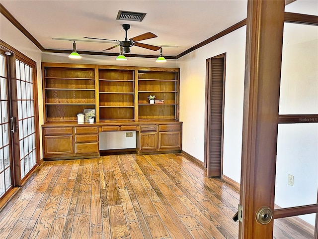 unfurnished office with ornamental molding, built in desk, light wood-type flooring, and french doors