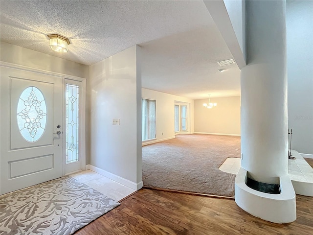 foyer with hardwood / wood-style flooring, a textured ceiling, and an inviting chandelier