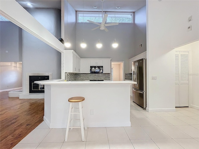 kitchen with white cabinets, a kitchen breakfast bar, stainless steel fridge, ceiling fan, and kitchen peninsula