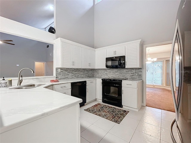 kitchen with sink, white cabinetry, kitchen peninsula, a towering ceiling, and black appliances