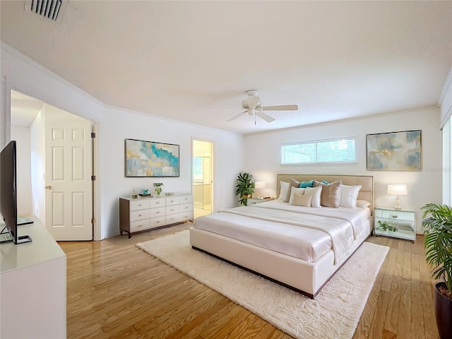 bedroom featuring light hardwood / wood-style flooring, ornamental molding, ceiling fan, and ensuite bathroom