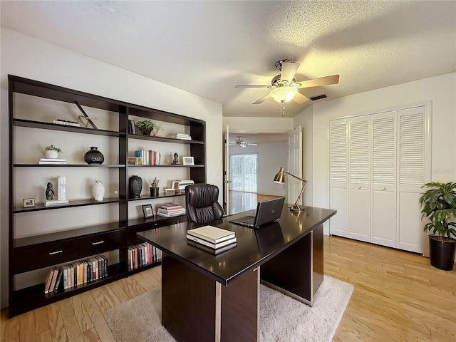 office with a textured ceiling, light hardwood / wood-style flooring, and ceiling fan