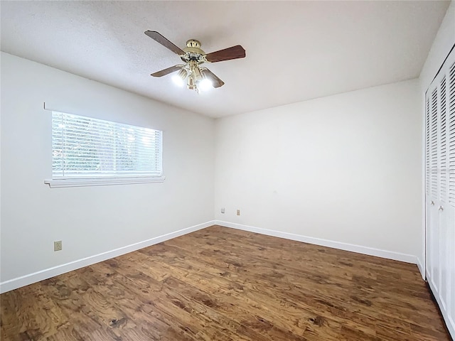 unfurnished bedroom with dark hardwood / wood-style flooring, a closet, and ceiling fan