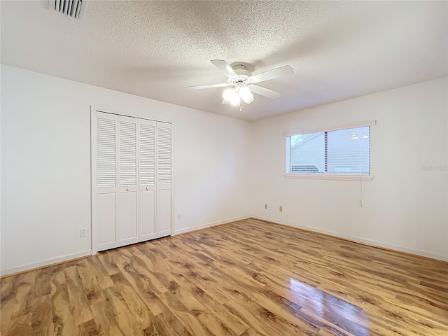 unfurnished bedroom featuring ceiling fan, a closet, a textured ceiling, and light wood-type flooring