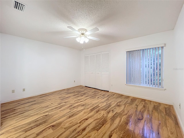 unfurnished bedroom with a closet, light hardwood / wood-style flooring, and a textured ceiling