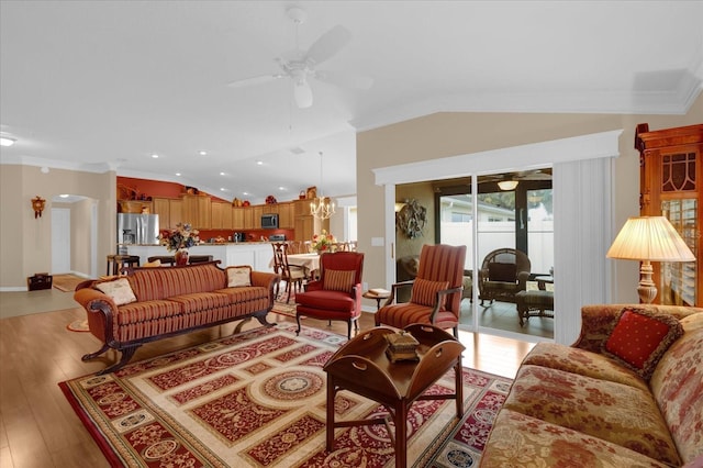 living room with crown molding, lofted ceiling, ceiling fan with notable chandelier, and light hardwood / wood-style flooring