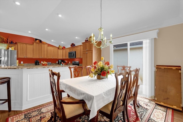 dining space featuring a notable chandelier, vaulted ceiling, plenty of natural light, and light wood-type flooring