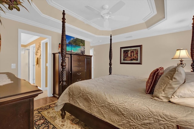 bedroom with crown molding, hardwood / wood-style floors, ceiling fan, and a tray ceiling