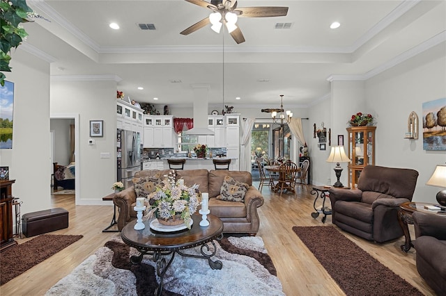 living room featuring ornamental molding, light wood-type flooring, and a tray ceiling