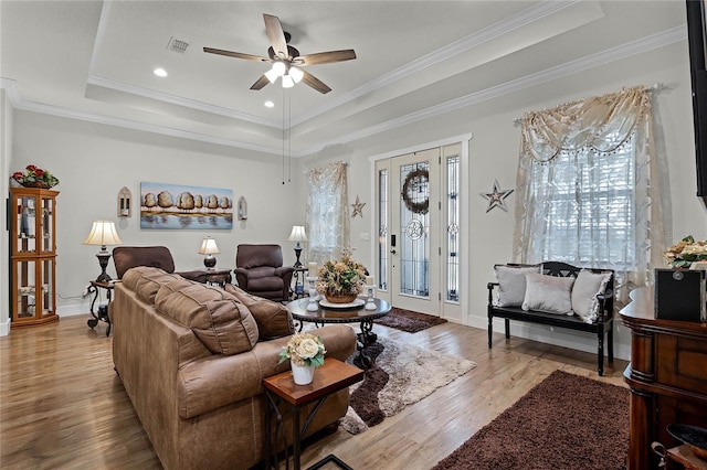 living room featuring ornamental molding, a raised ceiling, and light hardwood / wood-style floors