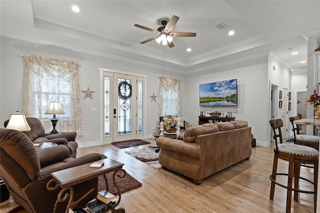 living room featuring a raised ceiling, ornamental molding, ceiling fan, and light hardwood / wood-style floors