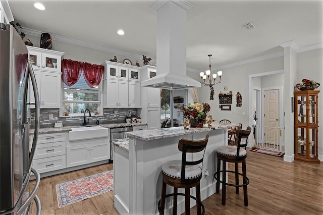 kitchen featuring white cabinetry, island range hood, stainless steel refrigerator, and a center island