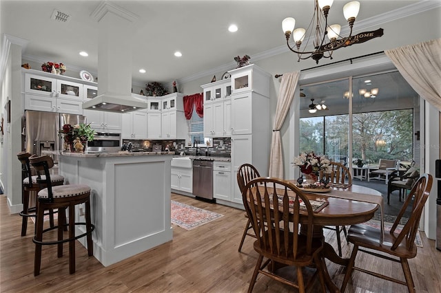 kitchen featuring a kitchen island, appliances with stainless steel finishes, pendant lighting, white cabinetry, and ornamental molding