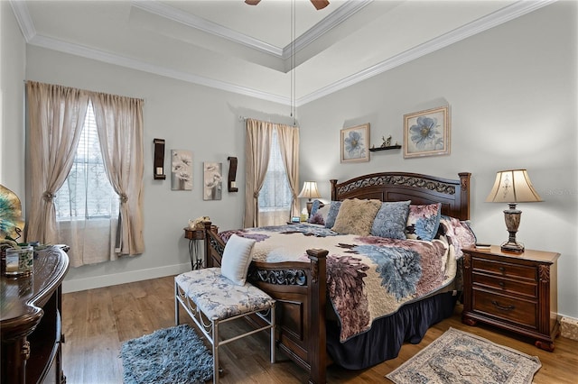 bedroom with crown molding, light wood-type flooring, and a tray ceiling