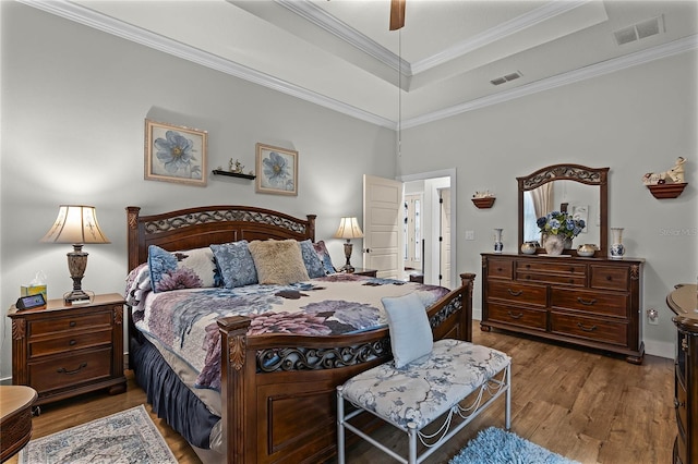 bedroom with crown molding, hardwood / wood-style flooring, a raised ceiling, and ceiling fan