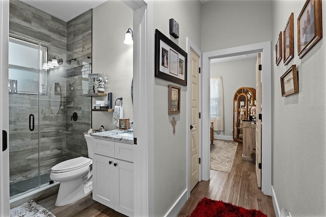 bathroom featuring hardwood / wood-style flooring, vanity, toilet, and a shower with door