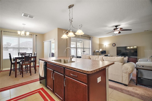 kitchen with light tile patterned flooring, sink, hanging light fixtures, a kitchen island with sink, and a textured ceiling