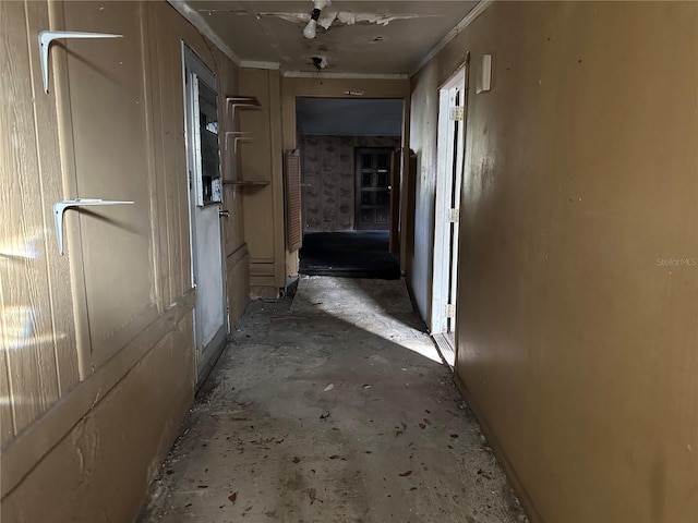 hallway with ornamental molding and concrete floors