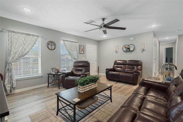 living room with ceiling fan, light hardwood / wood-style flooring, and a textured ceiling