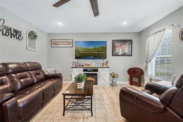 living room featuring a textured ceiling, light hardwood / wood-style flooring, and ceiling fan