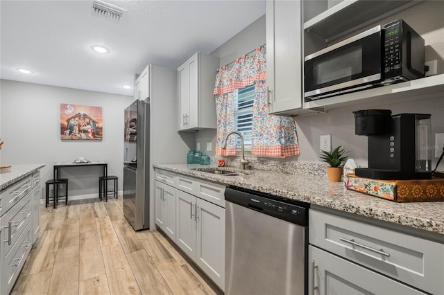 kitchen featuring appliances with stainless steel finishes, sink, and light stone counters