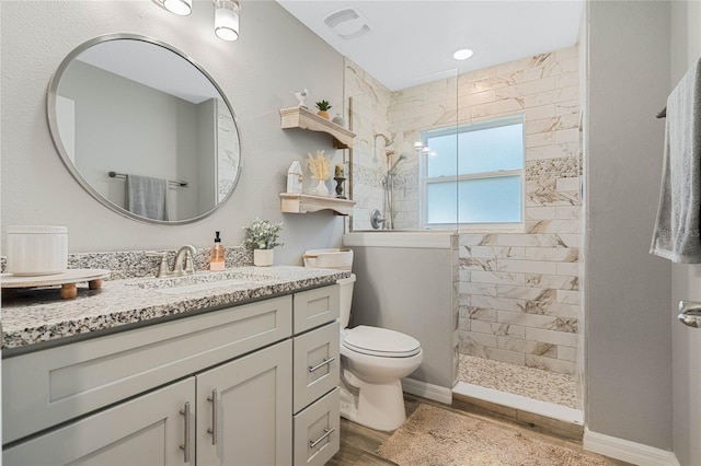 bathroom with vanity, wood-type flooring, toilet, and a tile shower