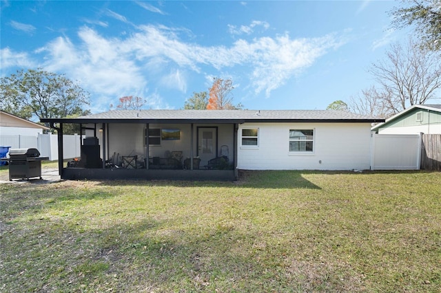 rear view of house featuring a yard and a sunroom