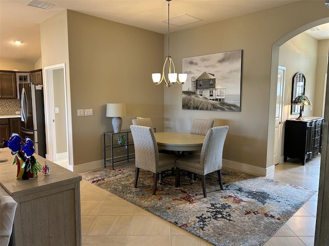 dining area featuring lofted ceiling, light tile patterned floors, and a notable chandelier