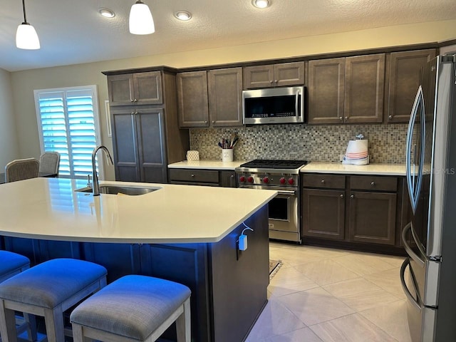 kitchen with pendant lighting, sink, a center island with sink, and appliances with stainless steel finishes