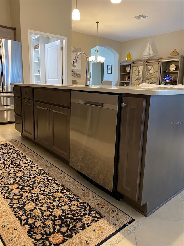 kitchen featuring dark brown cabinetry, stainless steel appliances, a chandelier, and light tile patterned flooring