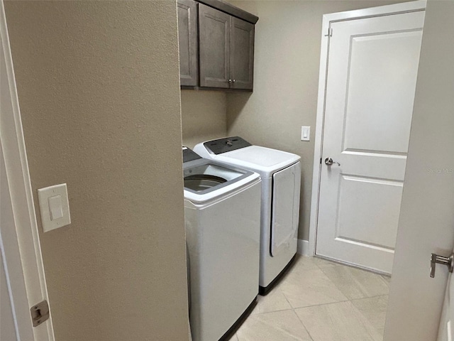 laundry area featuring cabinets, washer and dryer, and light tile patterned floors