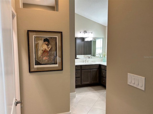 bathroom with tile patterned flooring, vanity, and lofted ceiling