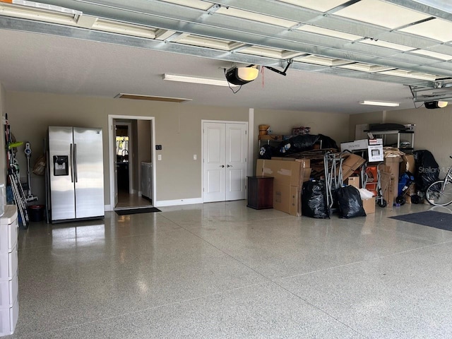 garage featuring stainless steel fridge with ice dispenser and a garage door opener