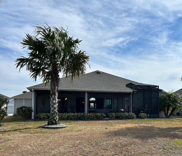 view of front of property featuring glass enclosure and a front lawn