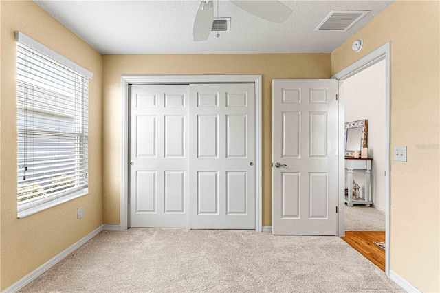 unfurnished bedroom featuring light carpet, ceiling fan, and a closet