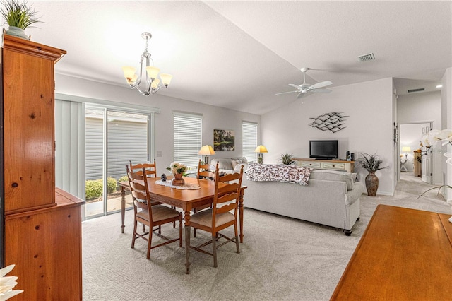 dining area with ceiling fan with notable chandelier, light colored carpet, and vaulted ceiling