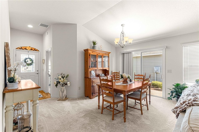 carpeted dining space with lofted ceiling and an inviting chandelier