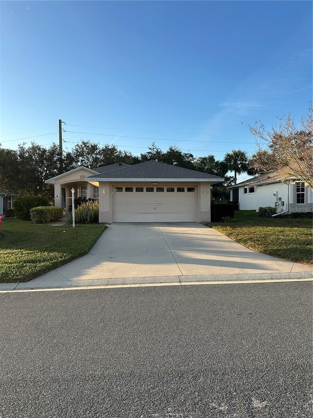 single story home featuring a garage and a front lawn