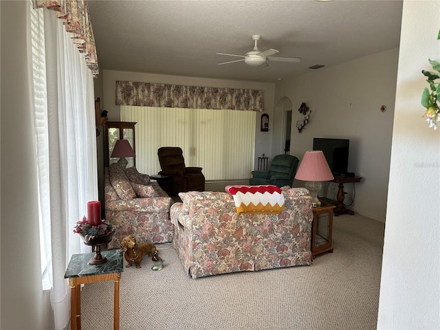 carpeted living room with a textured ceiling and ceiling fan