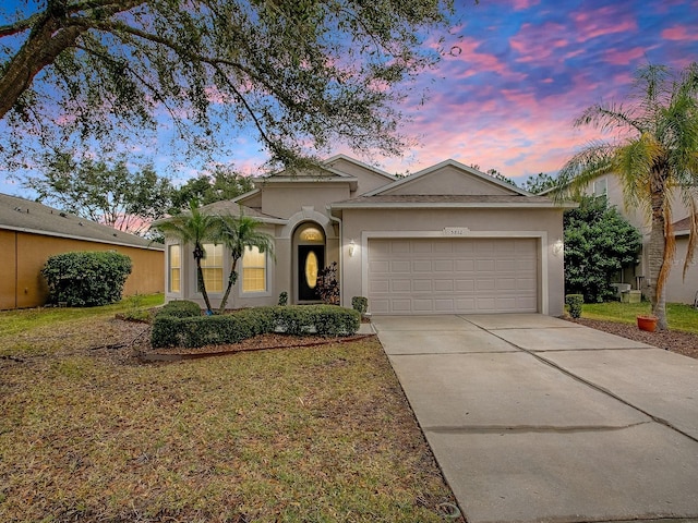 ranch-style house with a garage, a front yard, driveway, and stucco siding