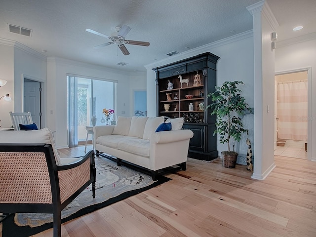 living room with light wood-type flooring, visible vents, and a textured ceiling