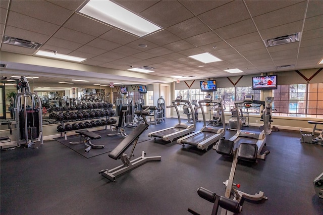 exercise room with a paneled ceiling, visible vents, and baseboards