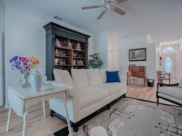 living area featuring visible vents, crown molding, a textured ceiling, and wood finished floors