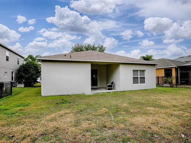 back of property with a patio area, a lawn, fence, and stucco siding