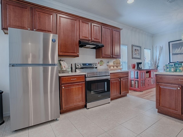 kitchen with light tile patterned floors, light countertops, appliances with stainless steel finishes, ornamental molding, and under cabinet range hood