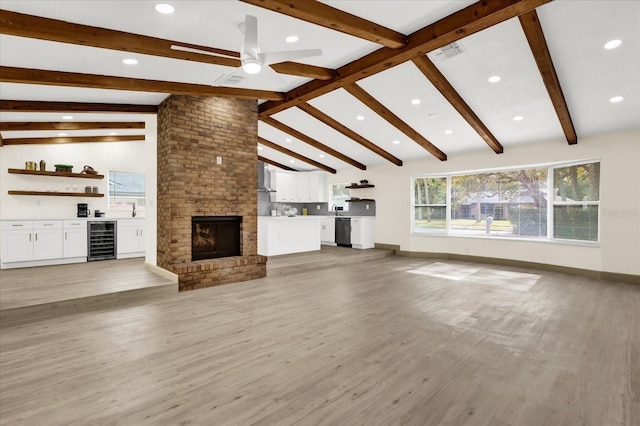 unfurnished living room featuring beverage cooler, visible vents, lofted ceiling with beams, ceiling fan, and a brick fireplace