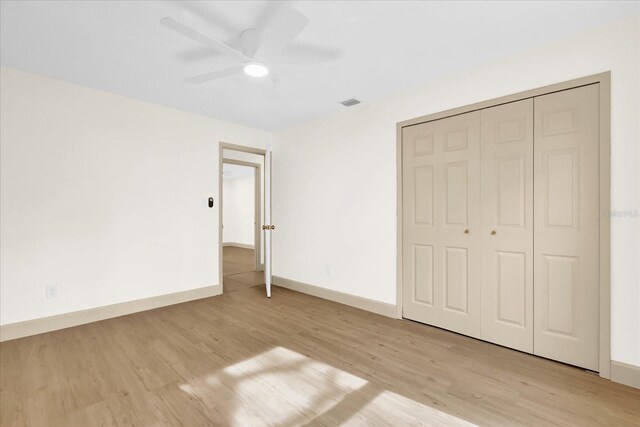 unfurnished bedroom with a closet, baseboards, ceiling fan, and light wood finished floors