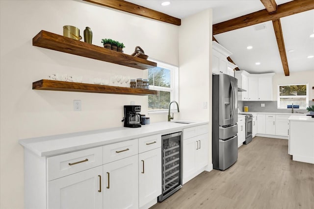 kitchen featuring white cabinets, wine cooler, stainless steel appliances, light countertops, and a sink