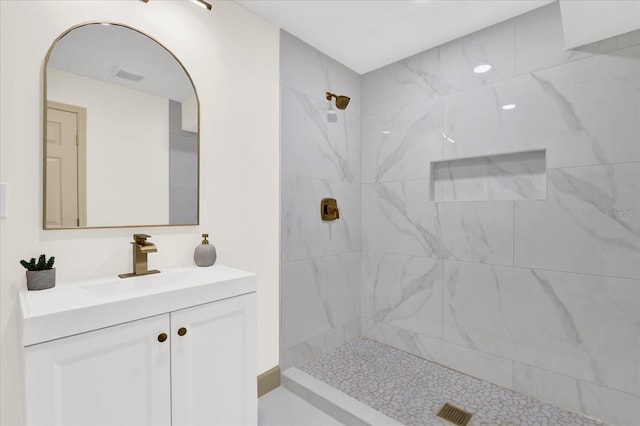 full bathroom with visible vents, tiled shower, and vanity