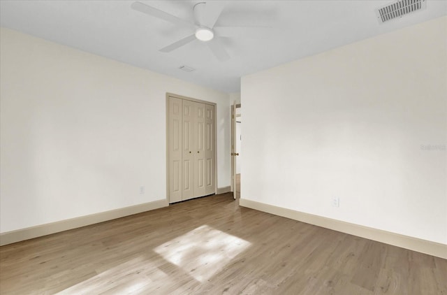 unfurnished room with light wood-style floors, baseboards, visible vents, and a ceiling fan